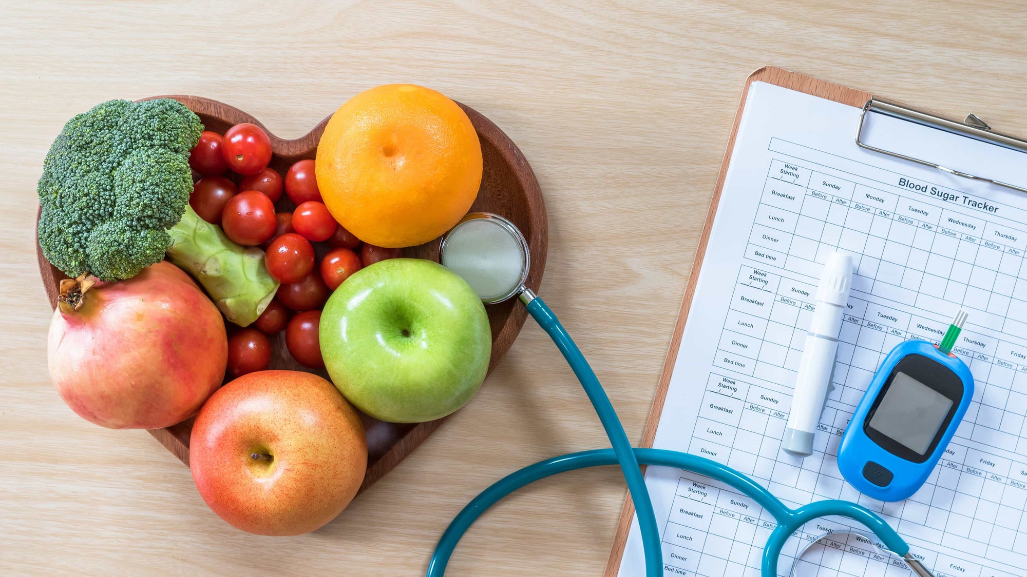 Diabetes blood sugar test alongside a heart-shaped bowl filled with fruits and vegetables