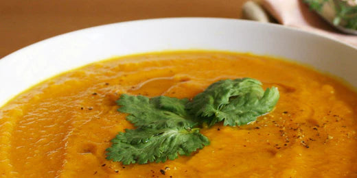 curried sweet potato soup presented in a white bowl with garnish