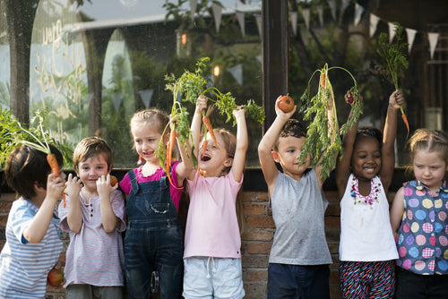 Group of children smiling and holding vegetables