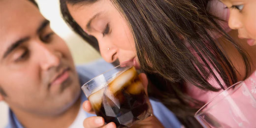 people watching a young woman drink iced soda from a glass