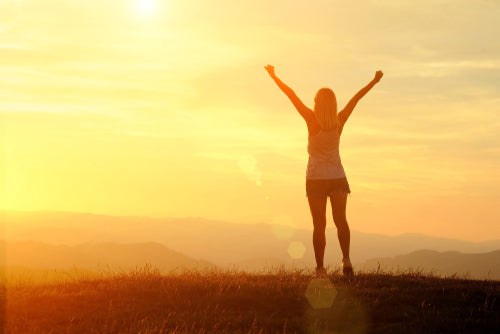 woman with arms outstretched against sunset