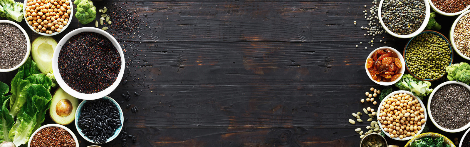 Wooden table with dried fruits, legumes, beans, and fresh vegetables