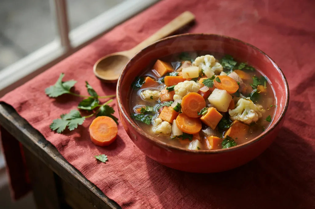 New Year's Resolution Soup - a red bowl of chunky vegetable soup with cauliflower and sweet potato