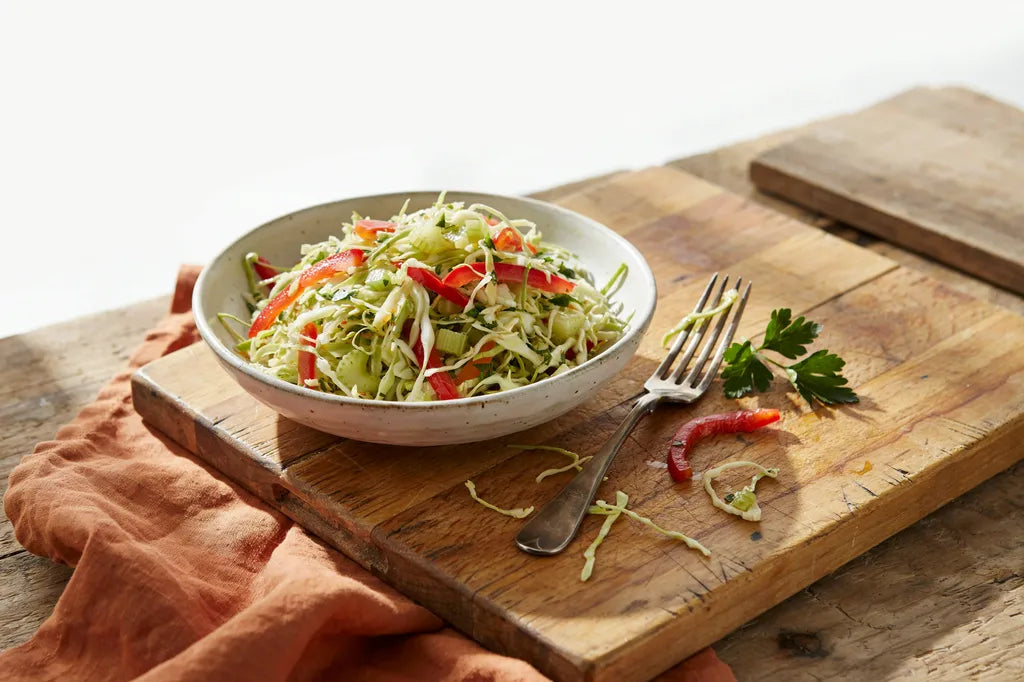 Slaw with Herbs - a white bowl of shredded cabbage slaw with red bell pepper and celery