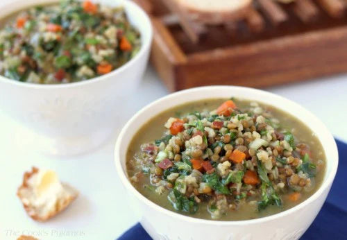 lentil and brown rice hearty vegan soup in white bowls on a kitchen counter
