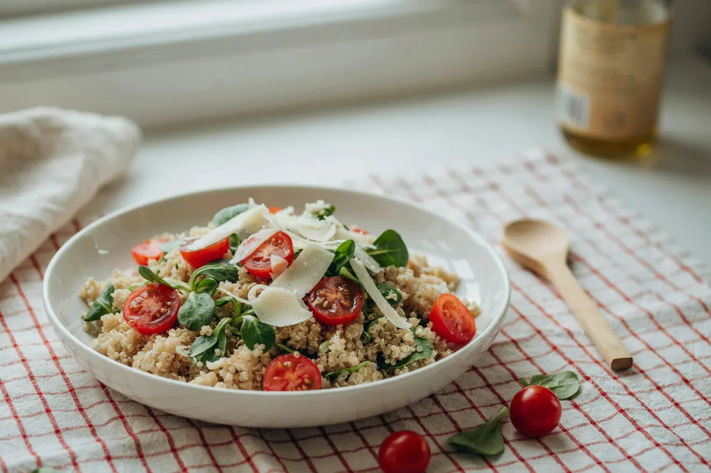 Radiant Quinoa Salad - a white bowl of quinoa salad with cherry tomatoes and spinach