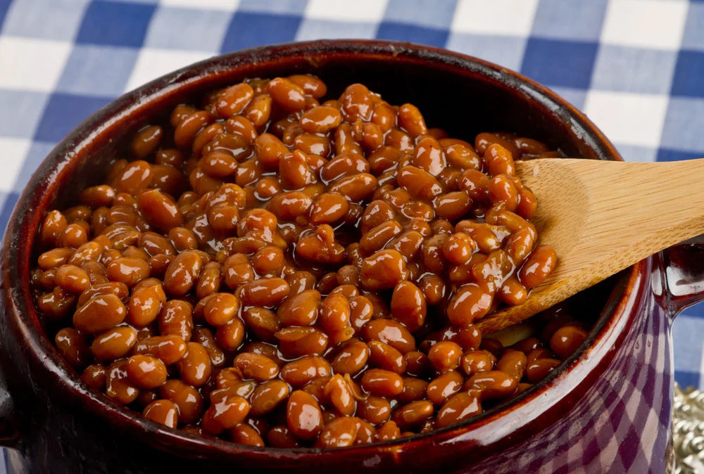 crock pot filled with baked beans with a large wooden spoon scooping a serving
