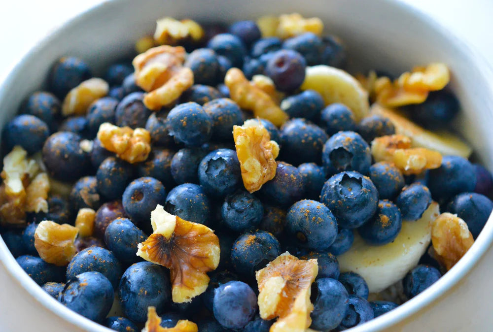 blueberries fruit bowl with walnuts and bananas shown up close in a white dish