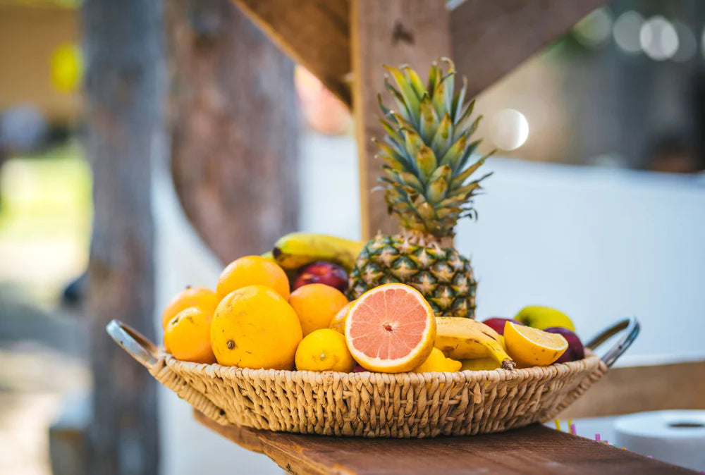 citrus and tropical fruits piled in a large basket sitting on top of a counter