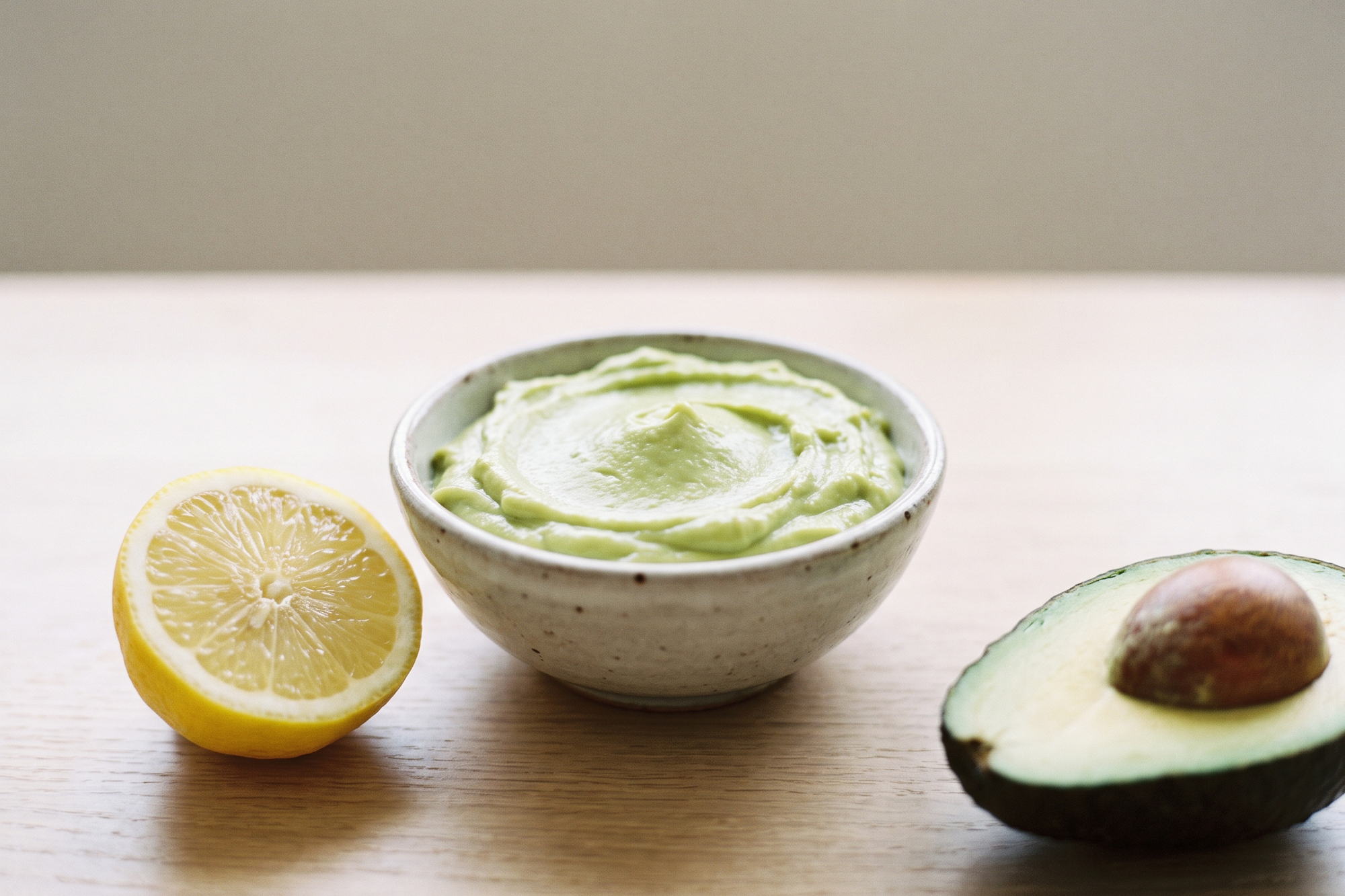 Bowl of raw avocado butter with a lemon half and an avocado