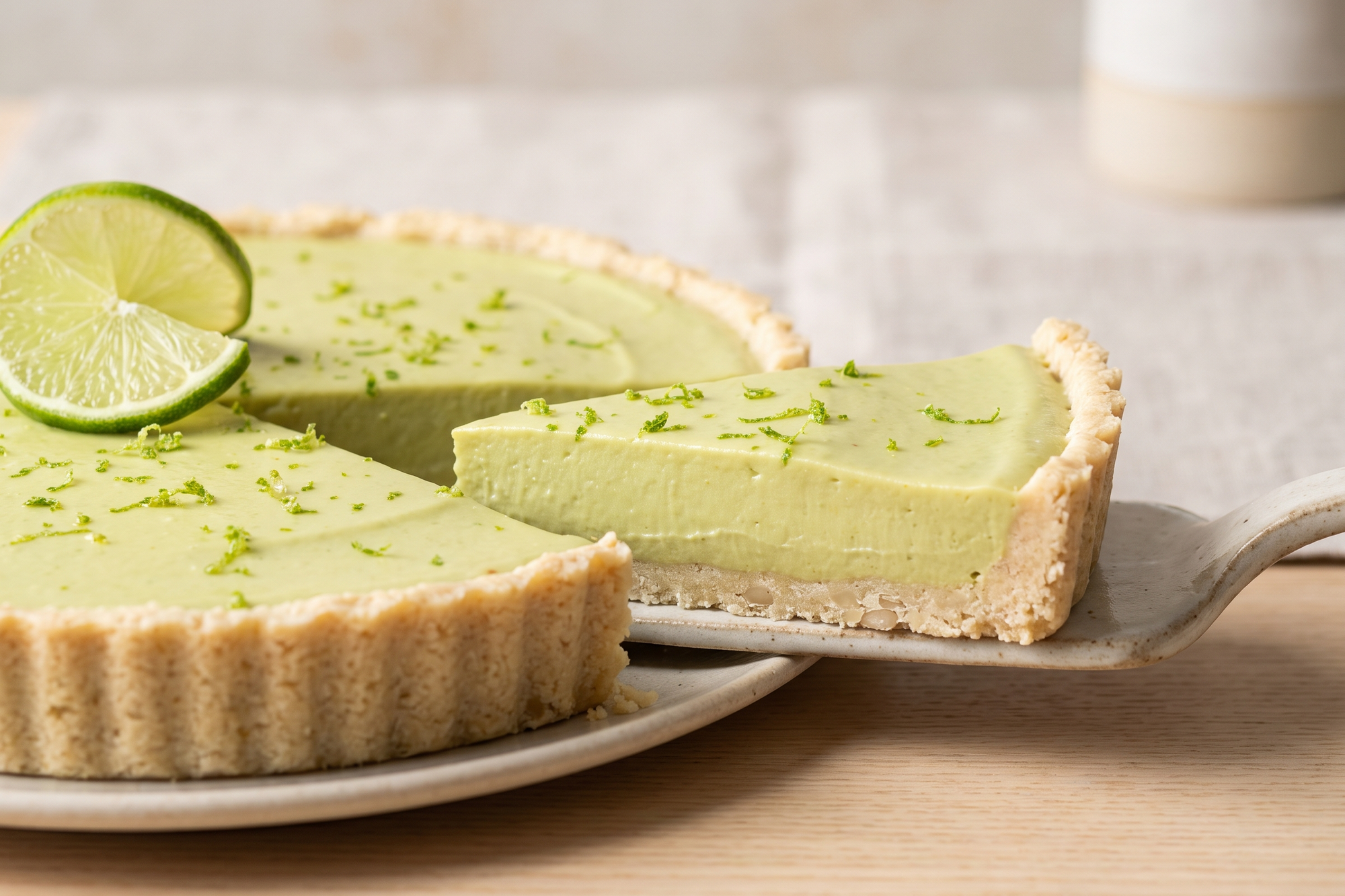 Simple key lime pie with a slice cut, garnished with lime zest and a lime wedge