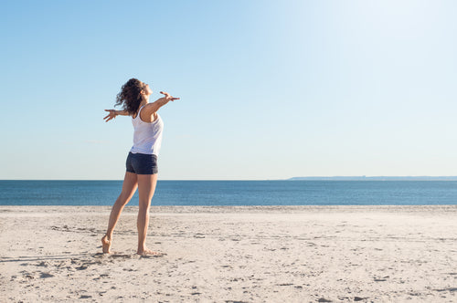 young woman with arms outstretched on beach