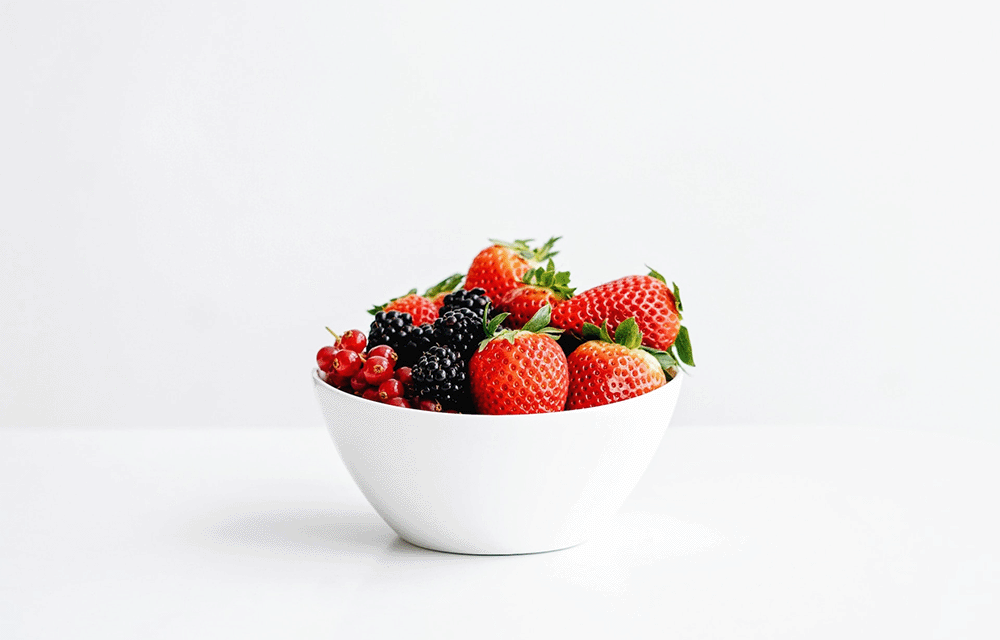 strawberries, blackberries, and currants in a ceramic bowl