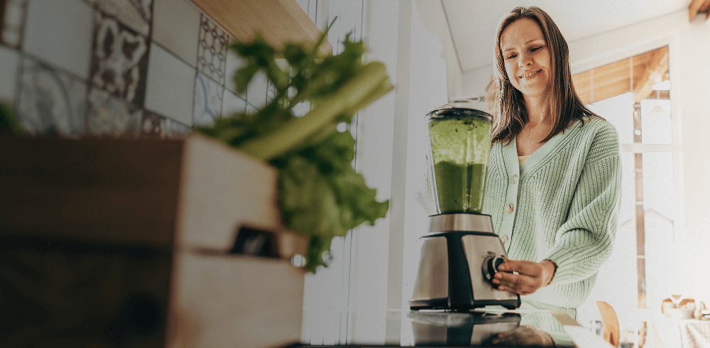 Woman with a blender preparing a green smoothie