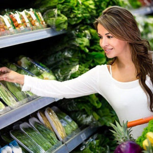Woman shopping in the vegetable produce aisle of the grocery store
