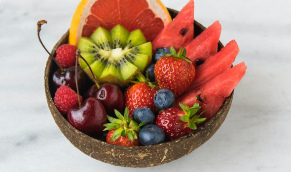 Natural bowl filled with raw fresh fruits, kiwi, watermelon, strawberries, cherries, blueberries