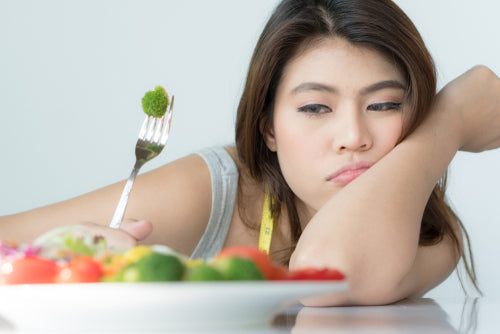 dieting woman looking at broccoli on fork